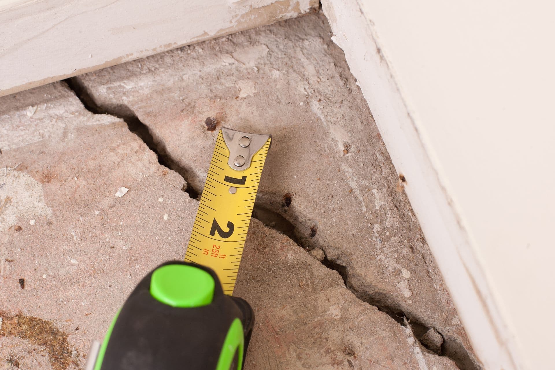 Measuring a large deep crack in concrete foundation of house