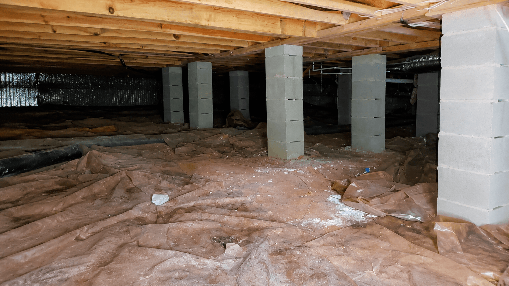 Dimly lit crawlspace beneath the house - The Perfect Place For Mold Growth: Your Unsealed Crawl Space